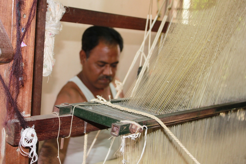 A weaver working behind the silk threads of a handloom in Kanchipuram